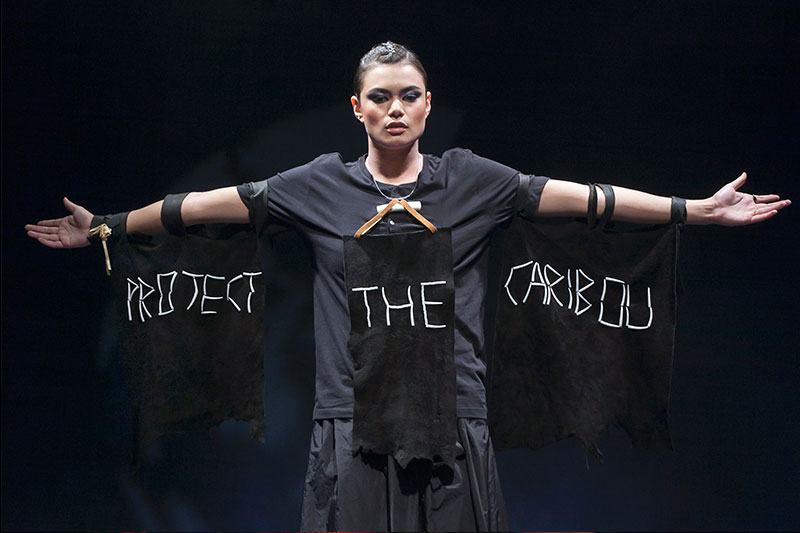 Female model dressed in black with “Protect the Caribou” written in white on her clothes