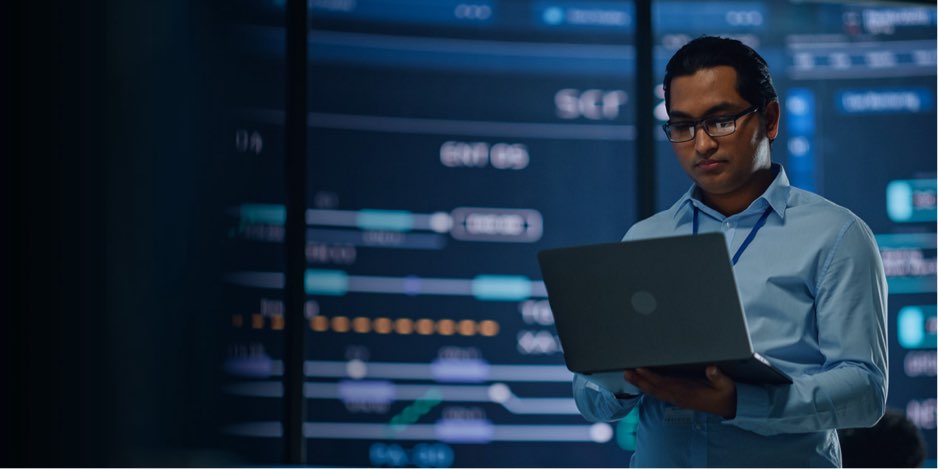 An IT expert in a control room operating from their laptop