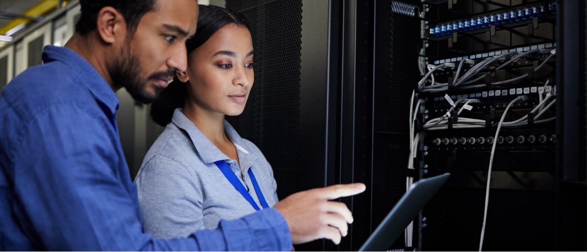 A woman and a man assessing a recovery service on a laptop in a server farm