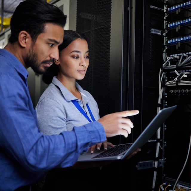 A woman and a man assessing a recovery service on a laptop in a server farm